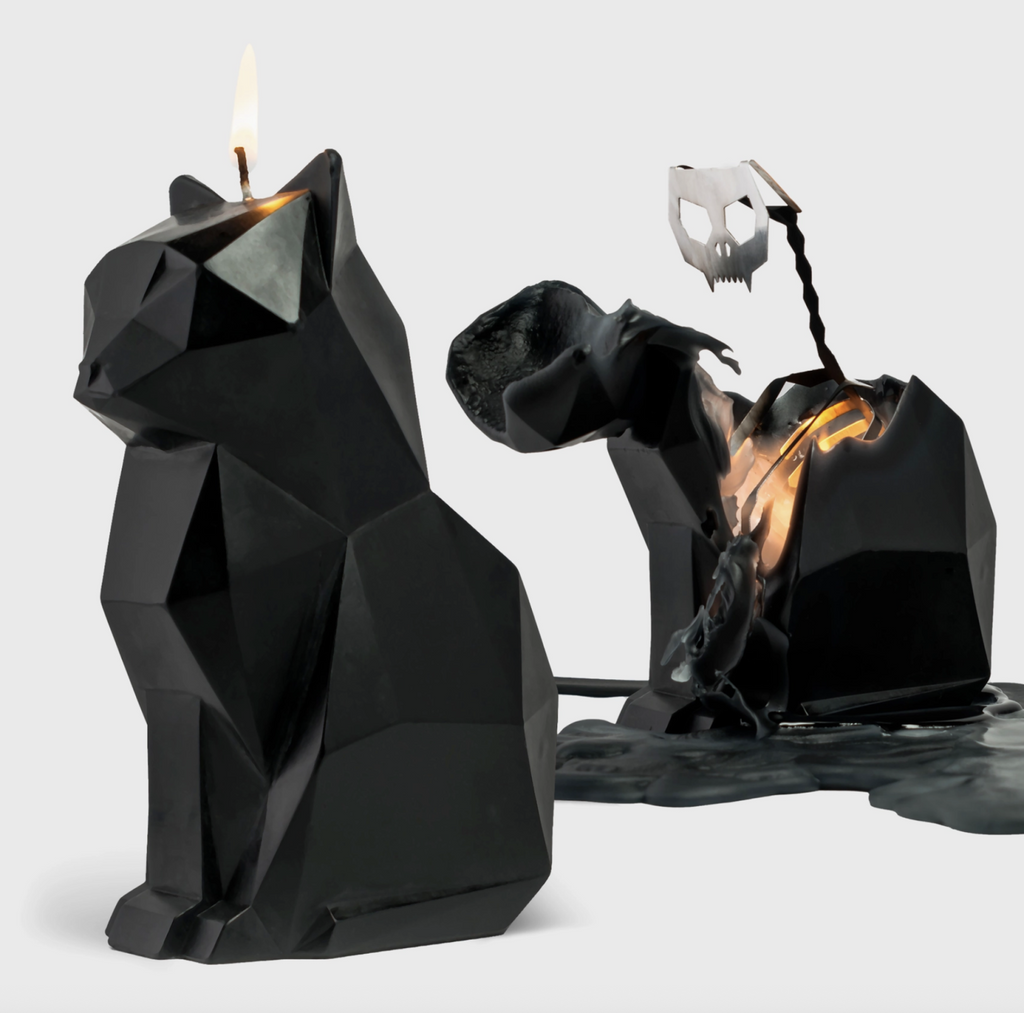 Black cat shaped candle burning down to reveal a metal skeleton inside on a white background.