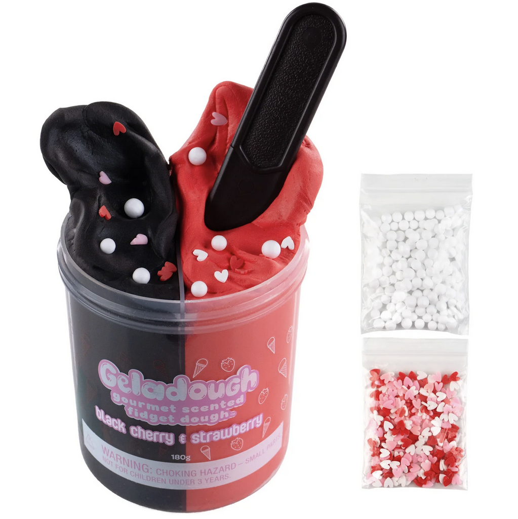 Clear container filled with two types of scented sensory dough. Black cherry scented dough is black while the strawberry scented dough is red, there is a toy spatula sticking out of the strawberry dough. To the side of the container are two bags, one has white beads and the other is filled with pink, red and white heart shaped confetti to mix into the dough. 