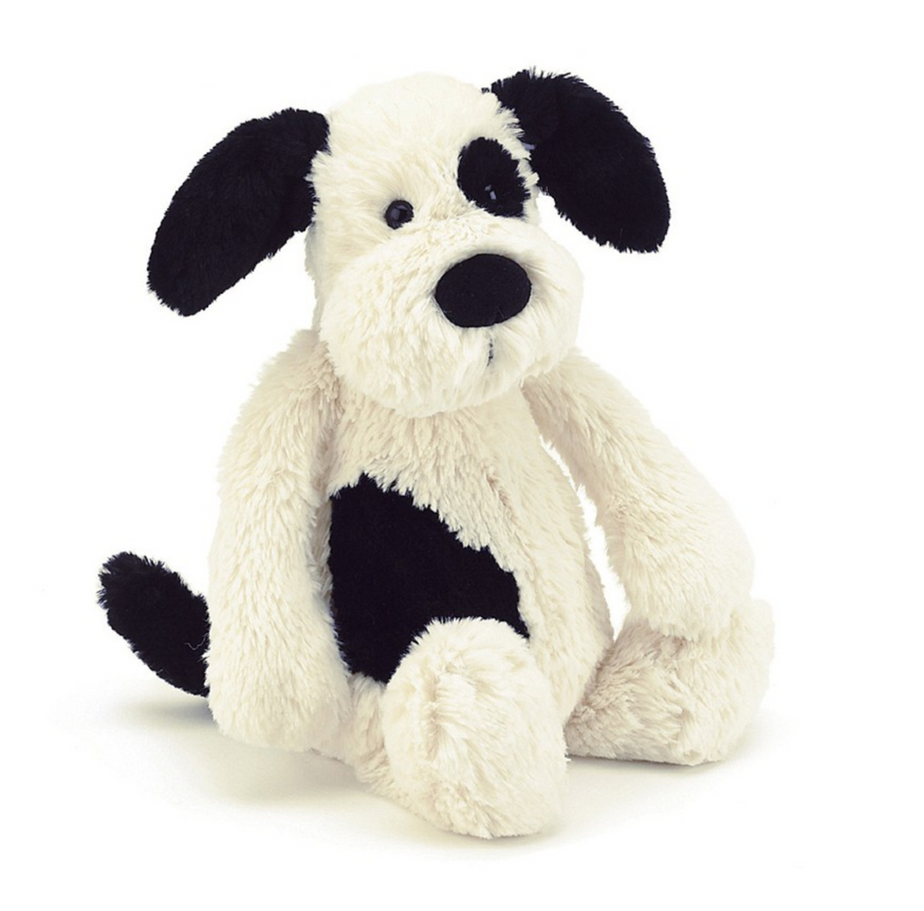 Black and cream colored plush puppy on a white background.