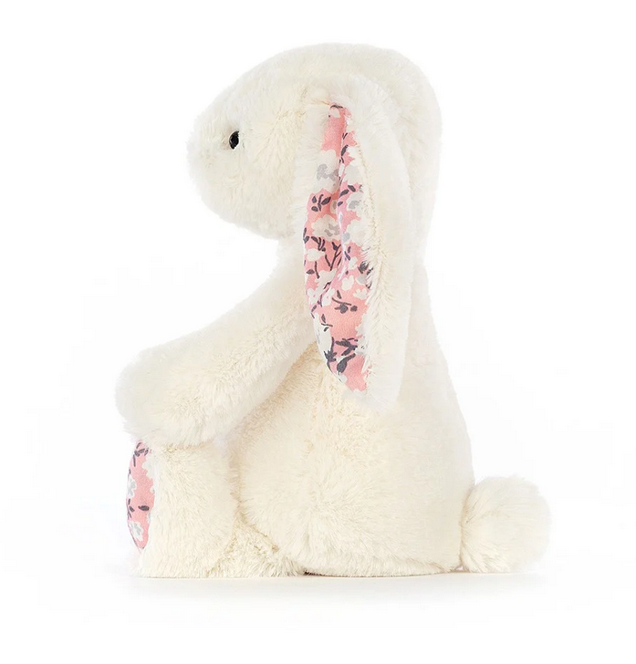 The small white bunny with it's cherry blossom print ears viewed from the side. 