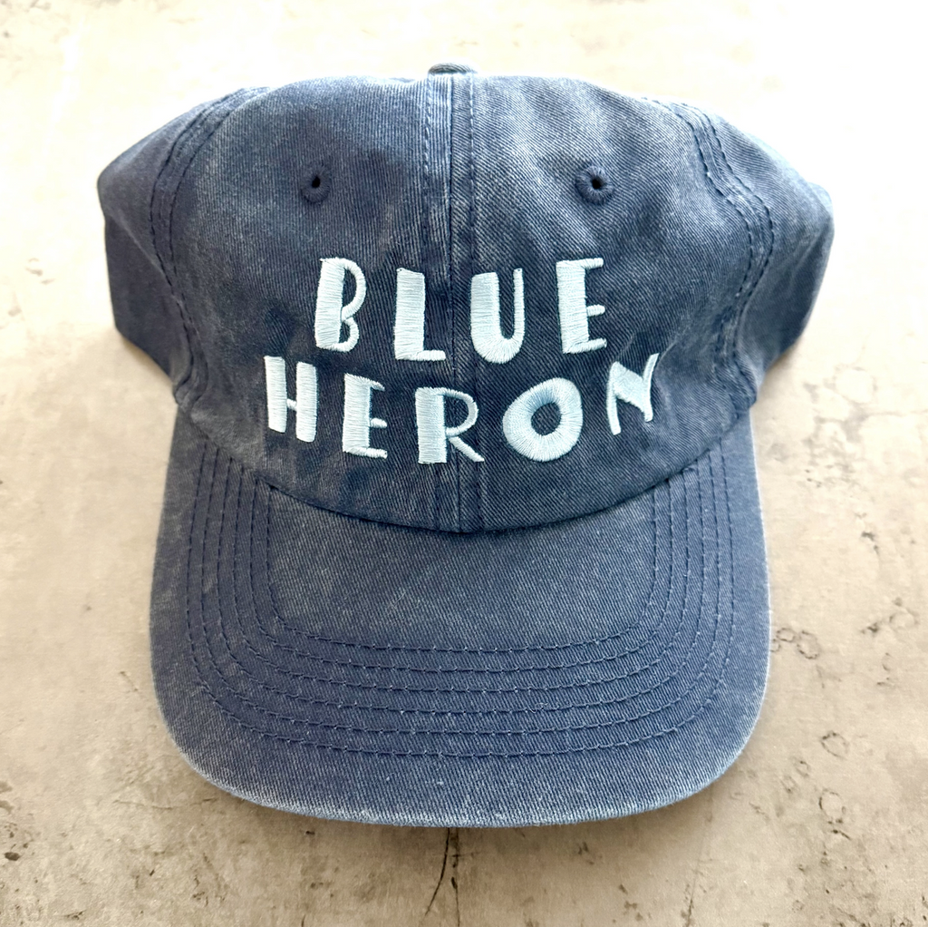 Blue ball cap with Blue Heron embroidered on the front in white. 