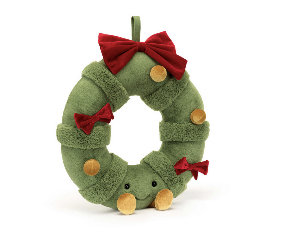 Plush green spruce wreath with a smiling face, gold feet, gold ornaments, and red ribbons.