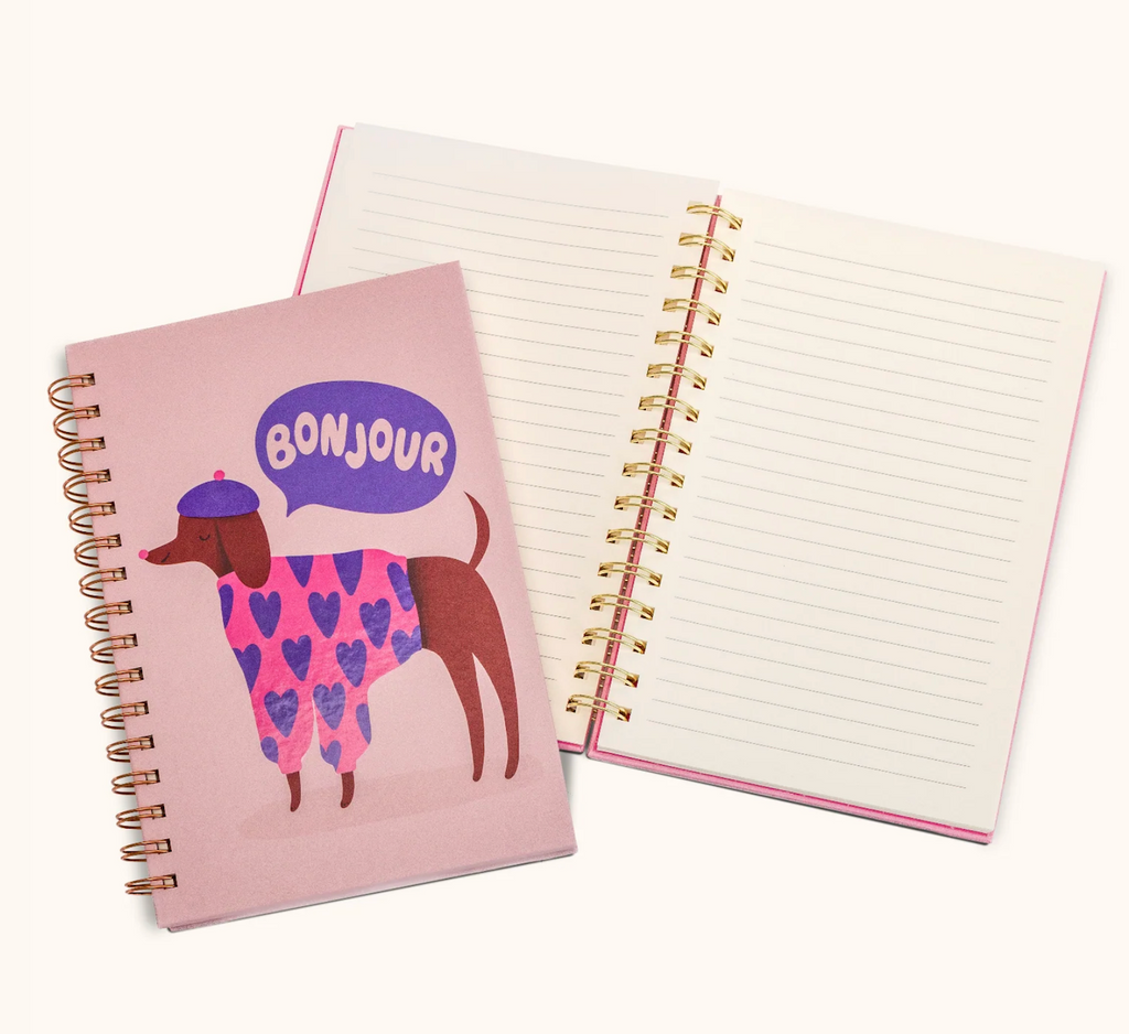 Notebook with a dog illustration and 'Bonjour' text on a pink cover, open to reveal lined pages.