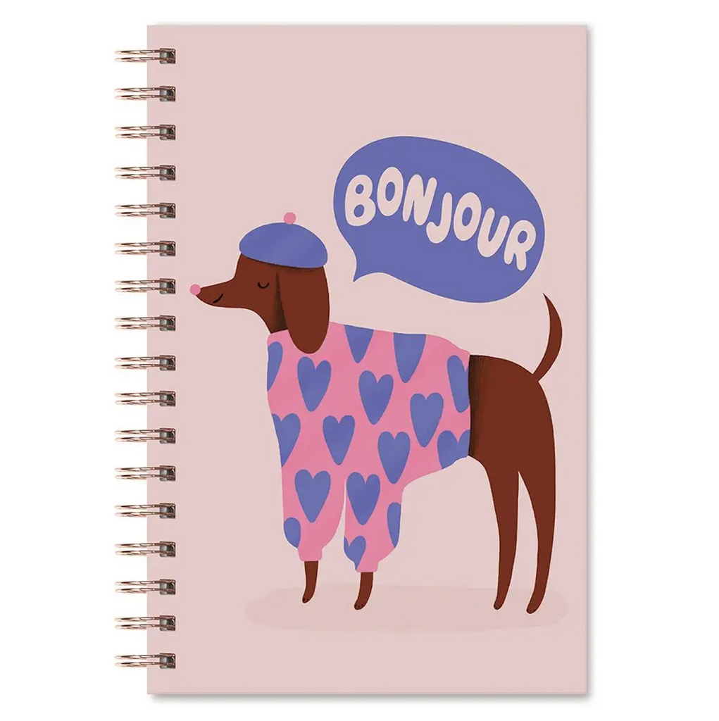 SPiral bound notebook with a dog wearing a pink sweater with blue hearts and a blue beret with a word bubble that reads "Bonjour" on the front cover. 
