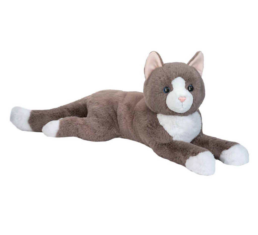 Jumbo sized stuffed animal of a grey cat with white paws, white chest and face, and white tipped tail stretched out  on it's stomach. 