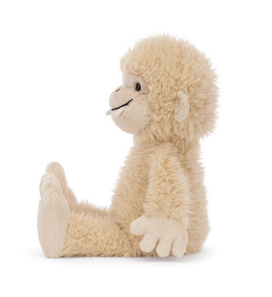 Plush bigfoot stuffed animal sitting up and facing sideways. 