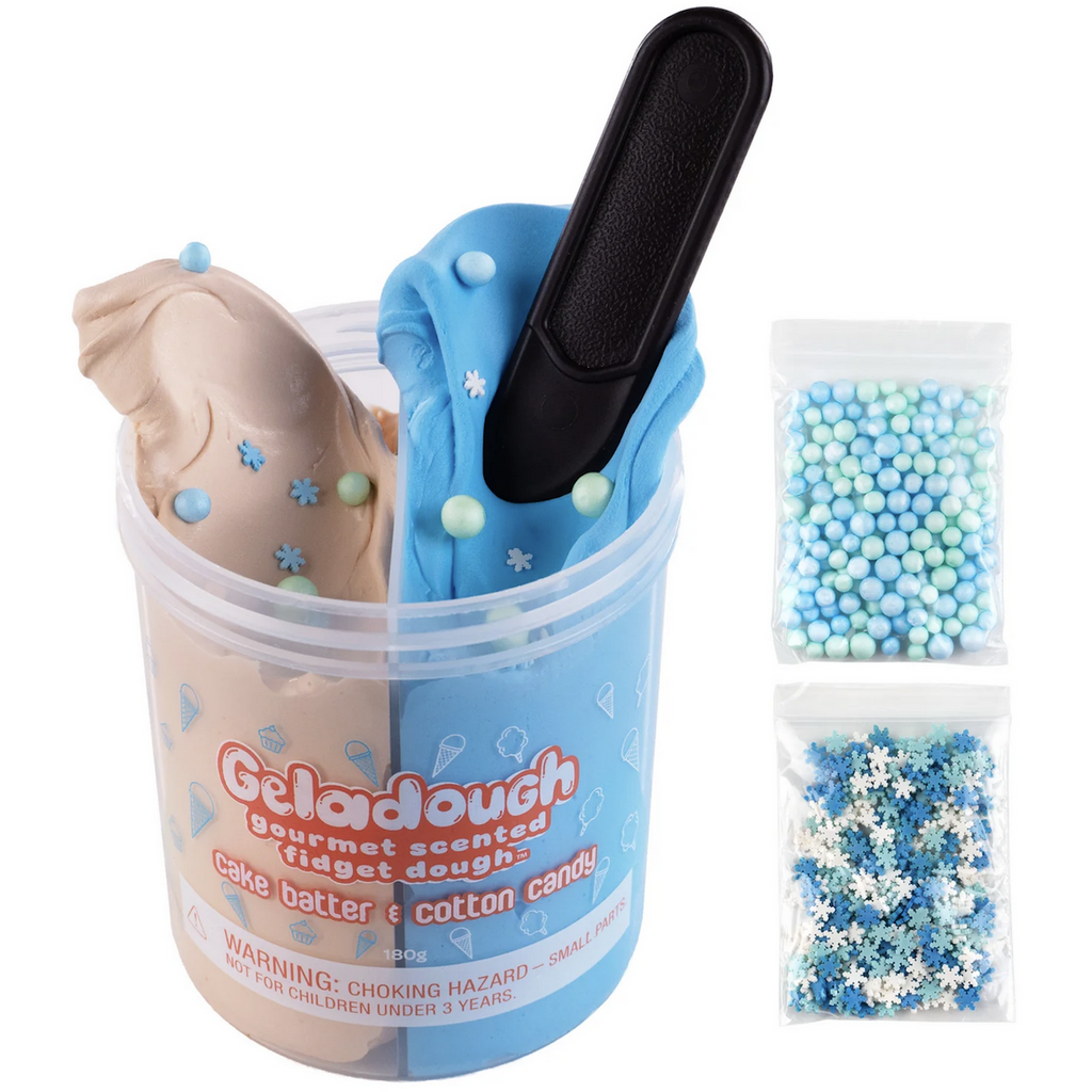 Container filled with two scented sensory dough. An off white colored dough scented like cake batter and a blue dough scented like cotton candy. There is a toy spatula sticking out of the blue dough. To the right of the container are two bags, one filled with iridescent blue and light green beads and the other with white, blue and green snowflake shaped confetti. 