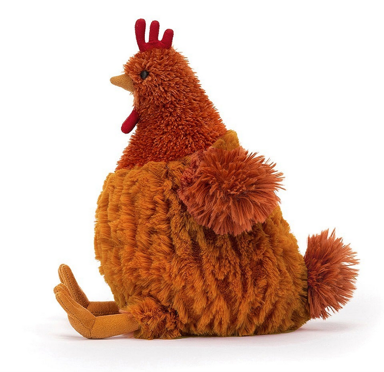 Cecile Chicken sitting upright and facing sideways giving a view of his bright red comb, orange fur wings and tail. 
