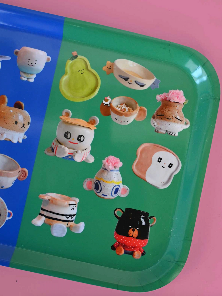 Colorful tray with pictures of ceramic food characters on the green half of the tray. 