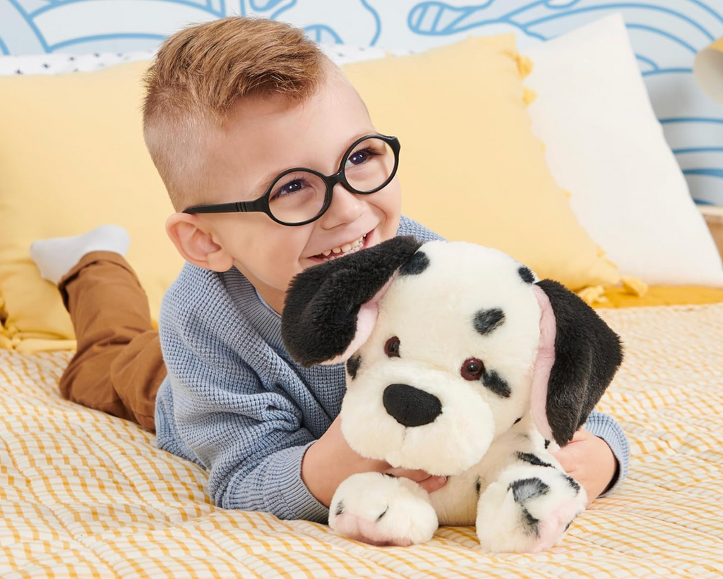 A young child laying down holding Checkers the Dalmatian plush toy. 