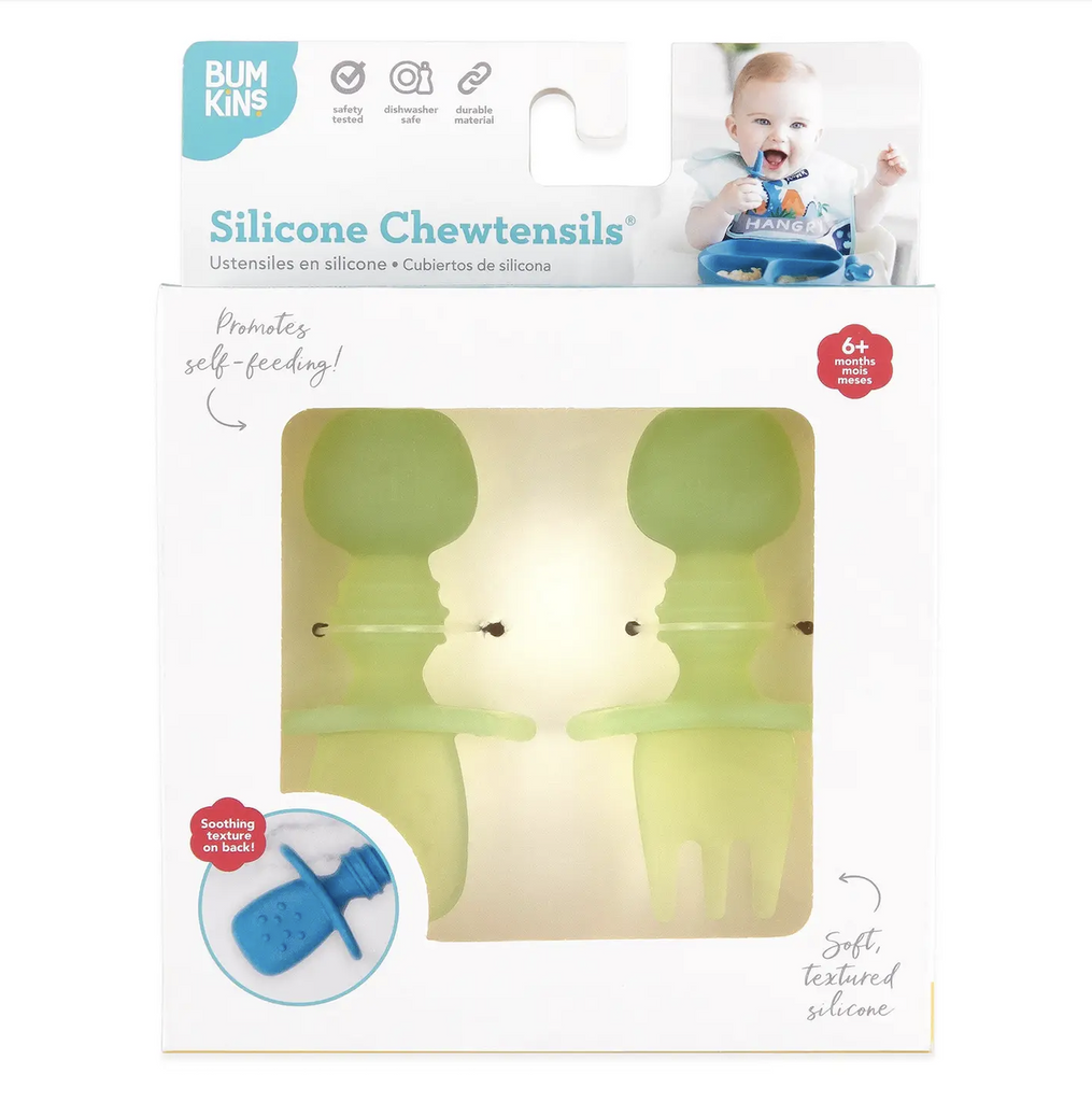 A white box with a clear window showing green Chewtensils which are chinky, silicone fork and spoon, sized for babies. 