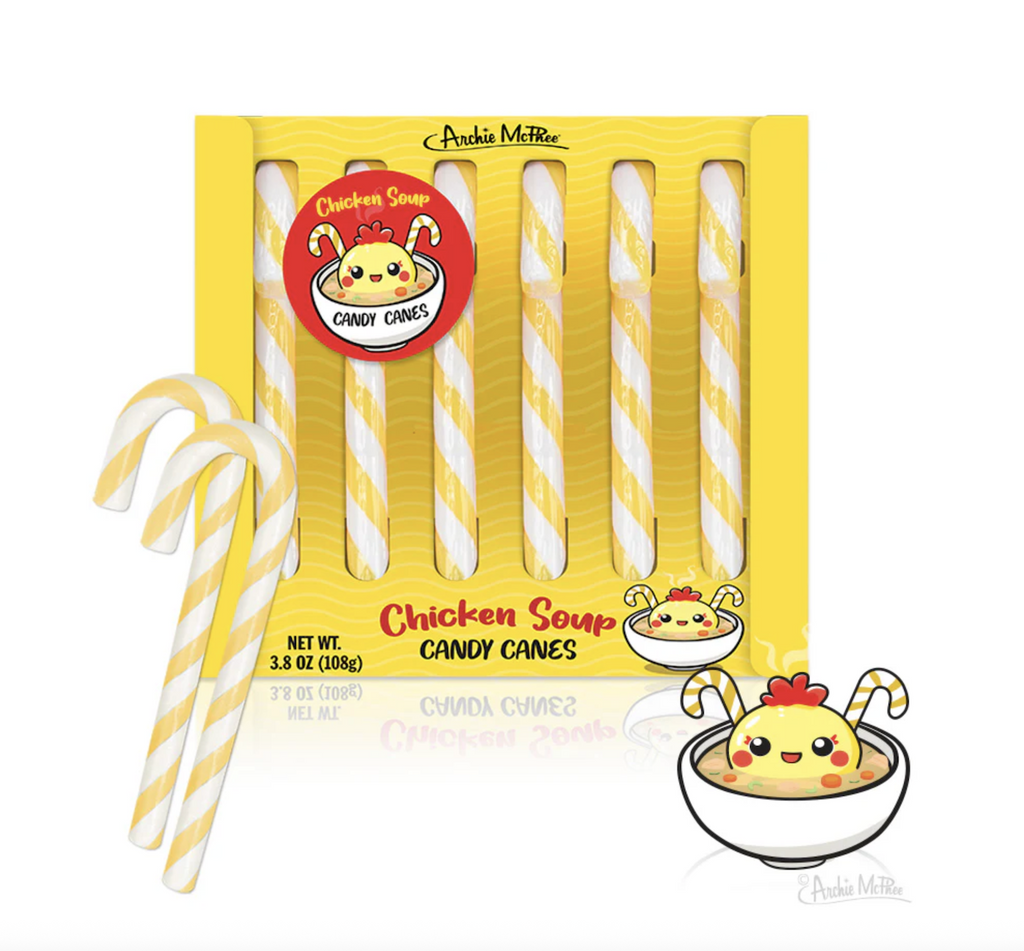 A bright yellow box filled with yellow and white striped candy canes  that are Chicken Soup flavored. There are illustrations of a chicken floating in a bowl of soup on the box. 