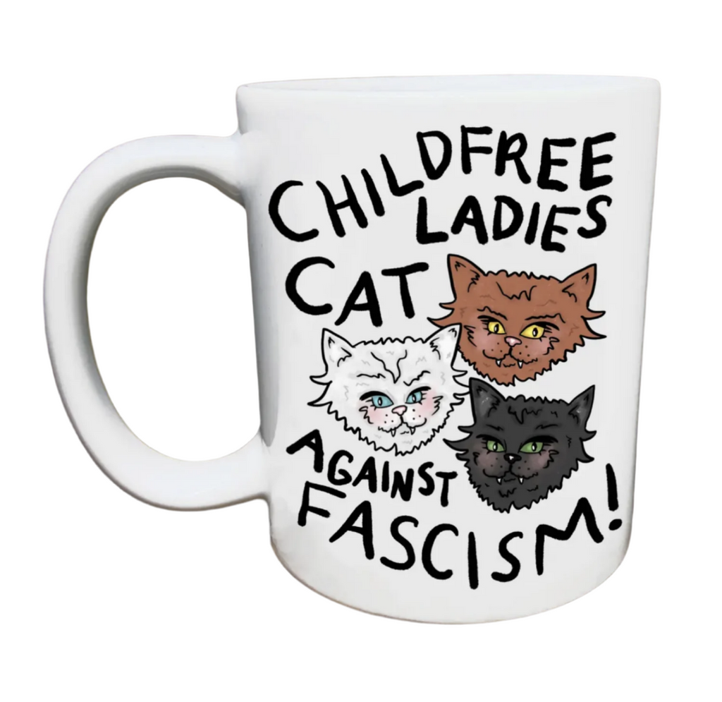 White ceramic mug with illustrated cat heads that reads "Childless Cat Ladies Against Fascism"