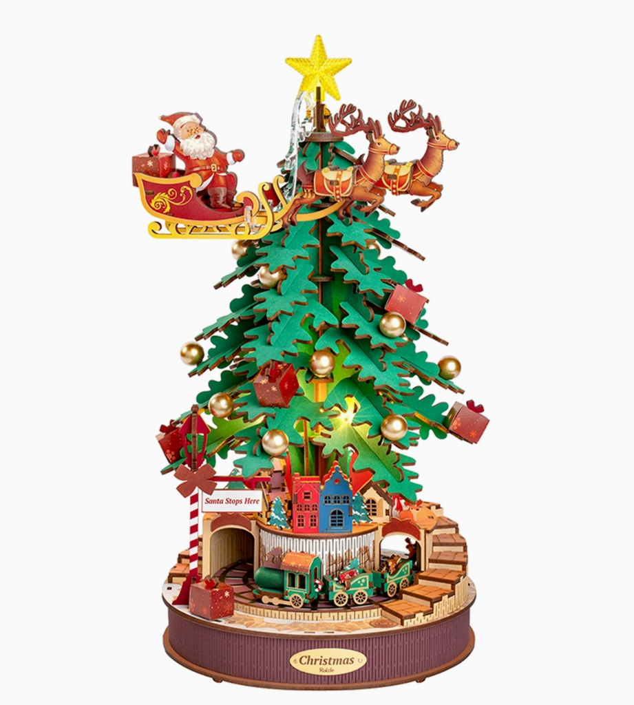 3D wooden puzzle of a Christmas tree with Santa Claus, reindeer, and sleigh on top, featuring lights and small buildings at the bottom. It is also a music box that plays a holiday tune and turns. 