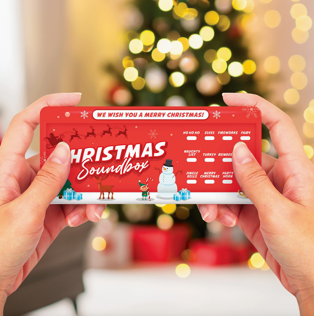 Red Christmas soundbox held by hands pressing the reindeer sound effect button. 