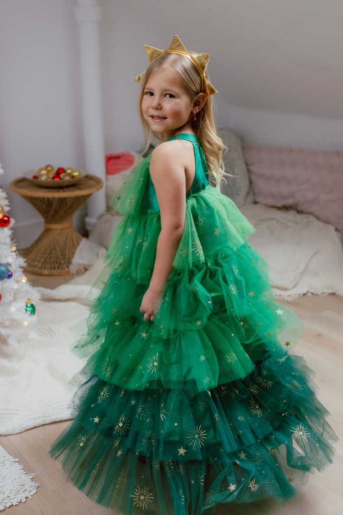 A young child wearing the Christmas Tree Dress and matching headband looking over her shoulder. 