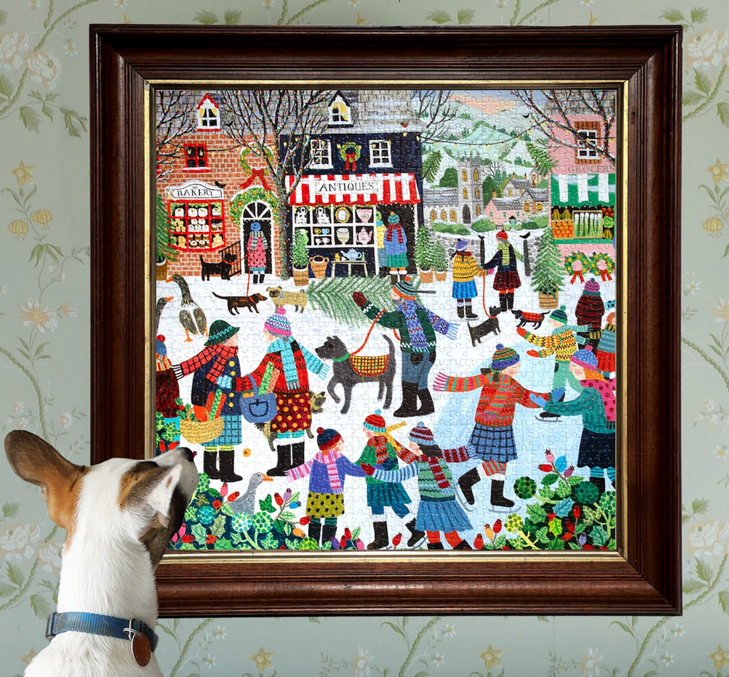 Framed artwork of Christmas In The Square a puzzle with a  winter scene with people and dogs, featuring a dog looking at the puzzle.  