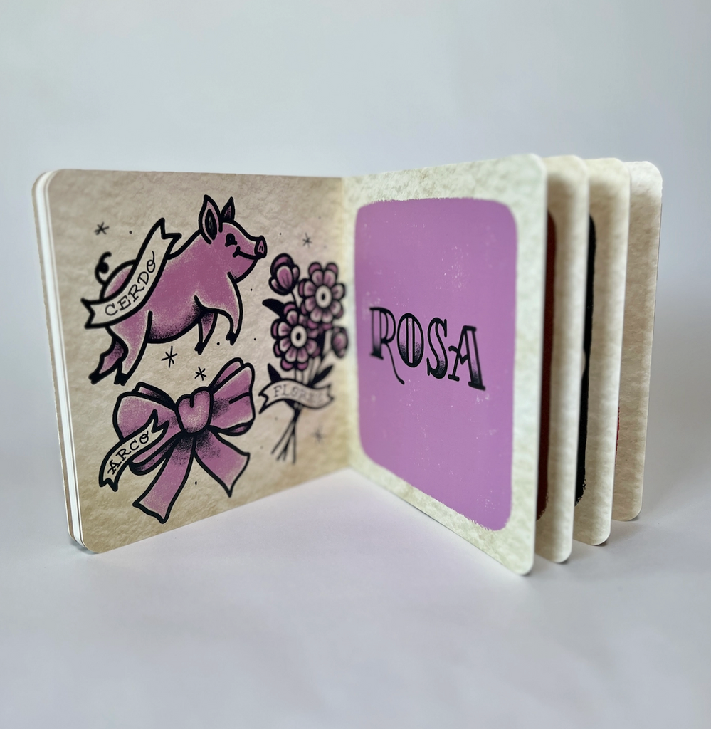 Colores de Tatuajes opened to interior pages with illustrations of a pig, bow, and flowers on one page and the name 'Rosa' on the other, all illustrated in pinkish, purple color.