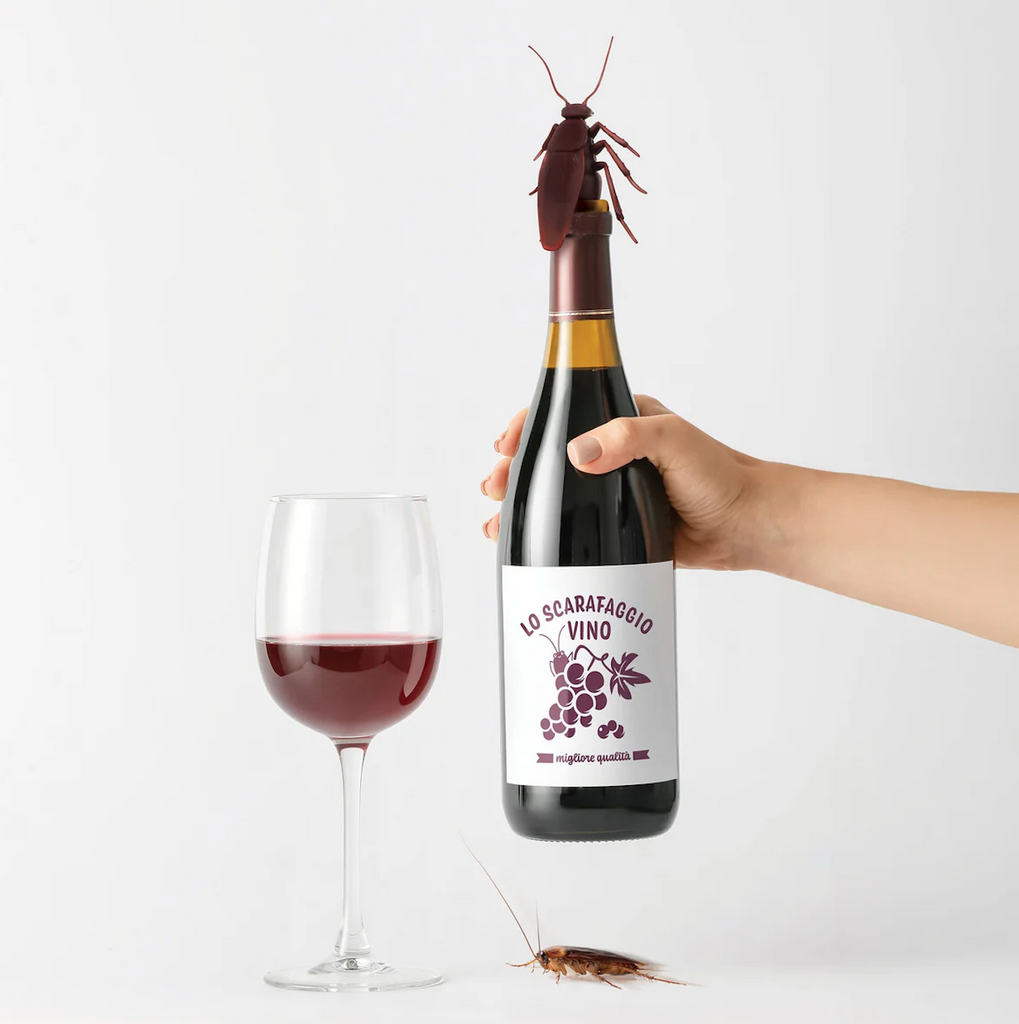 A bottle and glass of red wine with the "Corkroach" bottle stopper in the top of the bottle. 