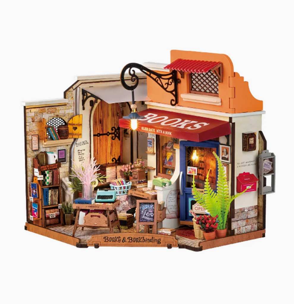 A close up view of the miniature Corner Bookstore fully assembled with the working LED lights illuminated and all of the miniature accoutrements included with the set. 