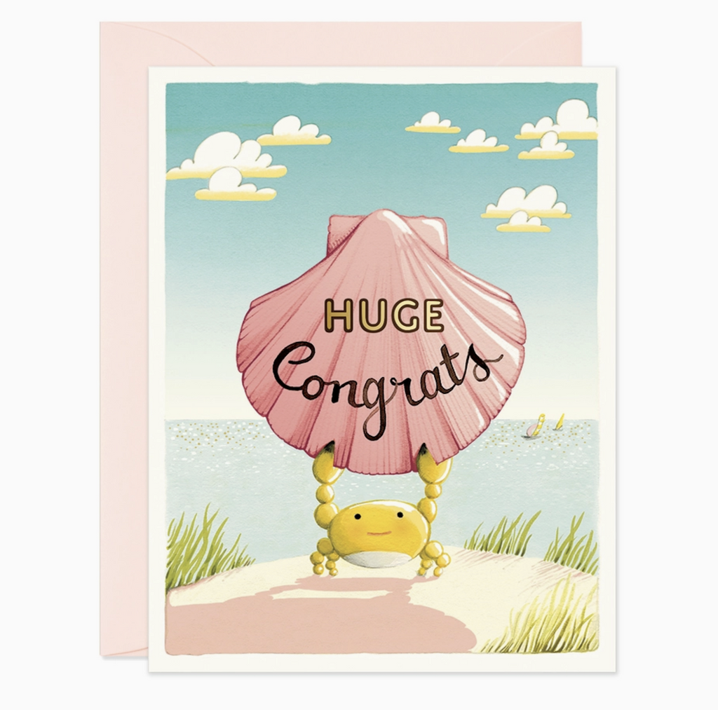 Beautifully illustrated greeting card of a crab standing on the shore holding a shell above it's head that reads "Huge Congrats" 