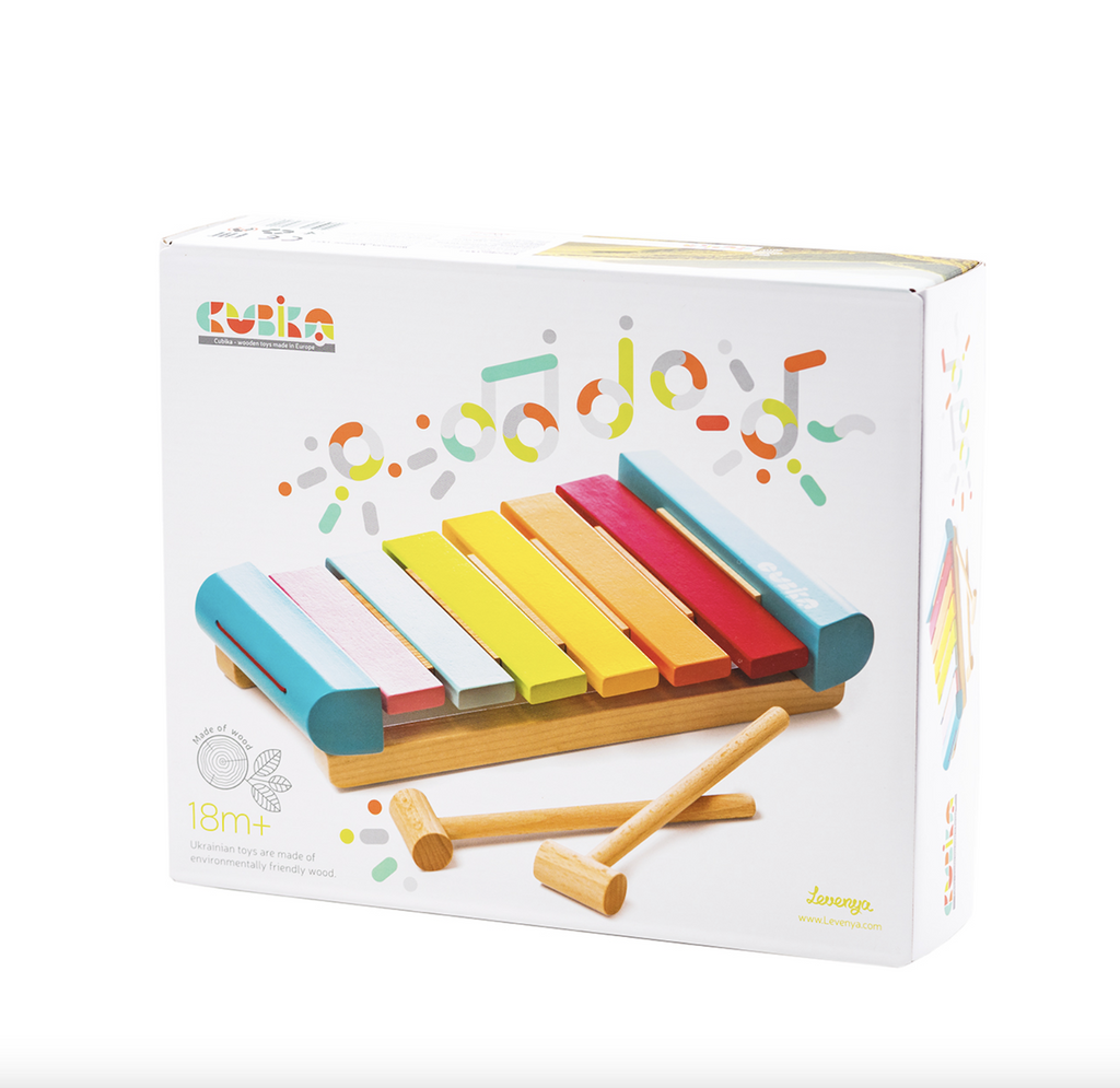 Box containing the xylophone by Cubika. The cover of the box features a picture of the colorful wooden xylophone with two wooden hammers and multicolored musical notes above the xylophone. 