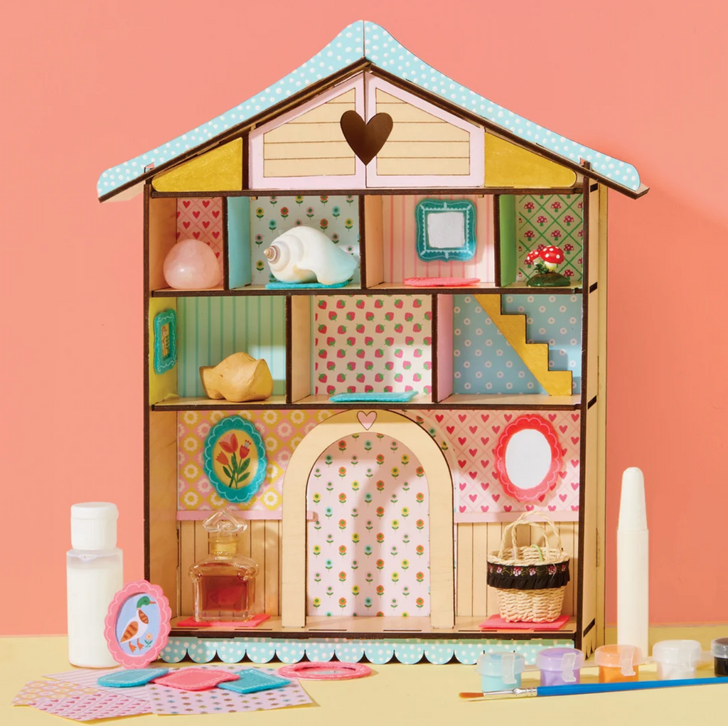 The Wooden Curio Cottage painted, and decorated with fabric with little collectibles placed in the cubbies. 