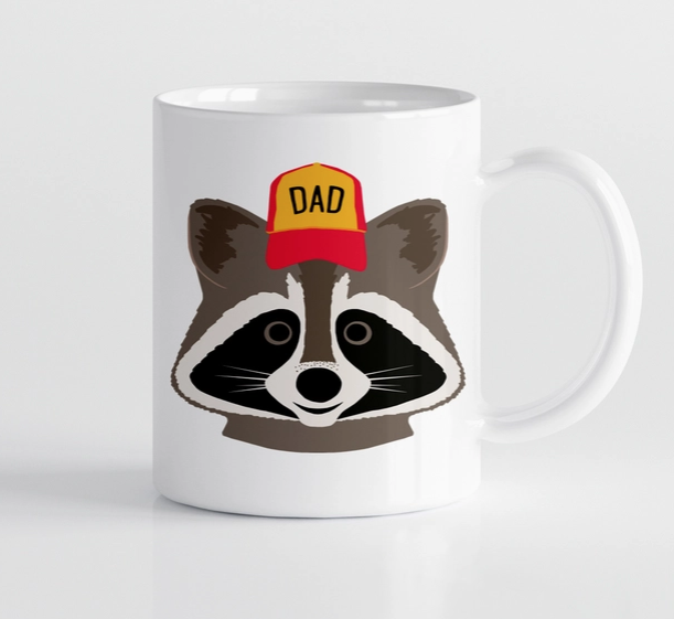 White ceramic mug with a smiling raccoon wearing a red and yellow ball cap that reads "Dad"