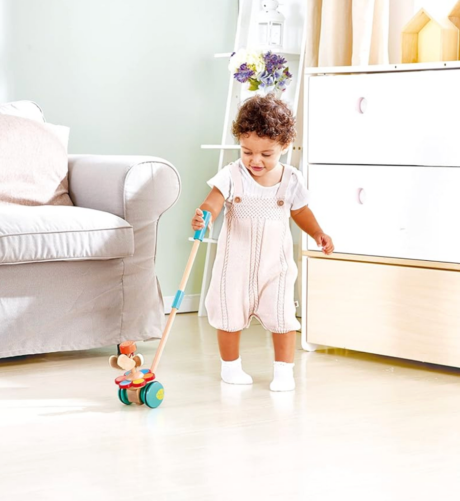 A toddler pushing the Dancing Butterflies Push Toy as they walk.