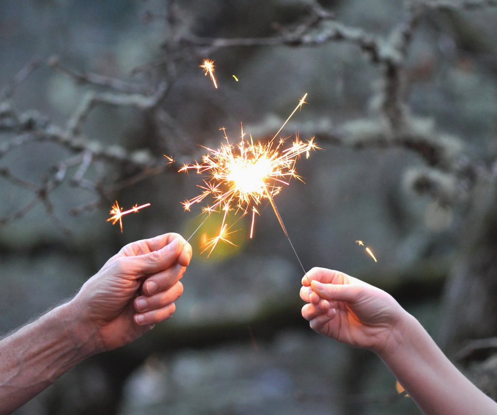 Two hands holding sparklers against a natural background