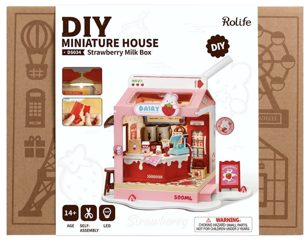 Packaging for the Strawberry Milk Box DIY Miniature House kit with a  color picture of the completed model with all of the miniature accessories. 