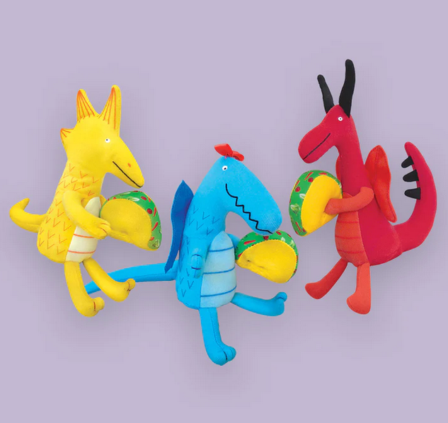 Three mini plush dragons on a purple background.. One blue dragon with wings holding a taco. One yellow dragon with spikes on it's head and an extra long tail holding a taco, and a red dragon with black horns and spiky tail, also holding a taco. 