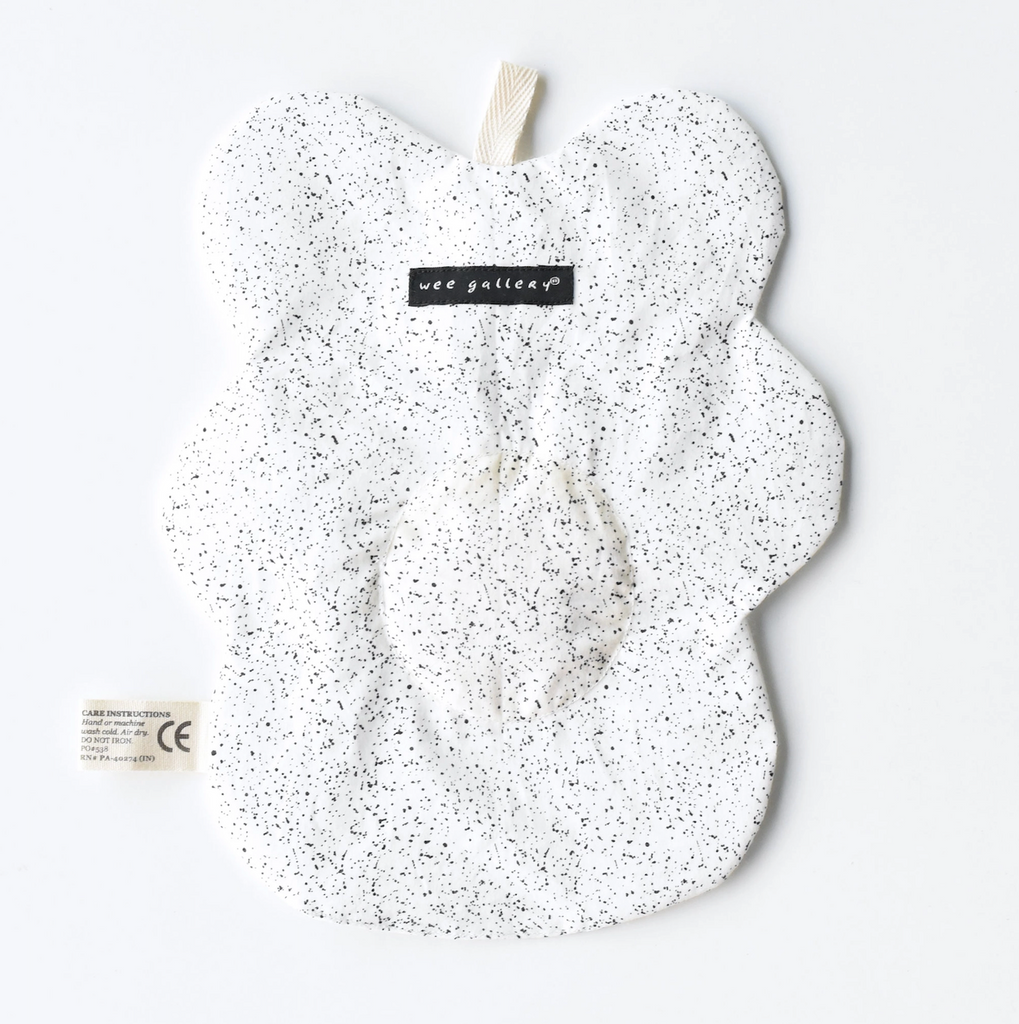 Back side of the Egg Crinkle Toy with a speckled pattern, shaped like a fried egg. 