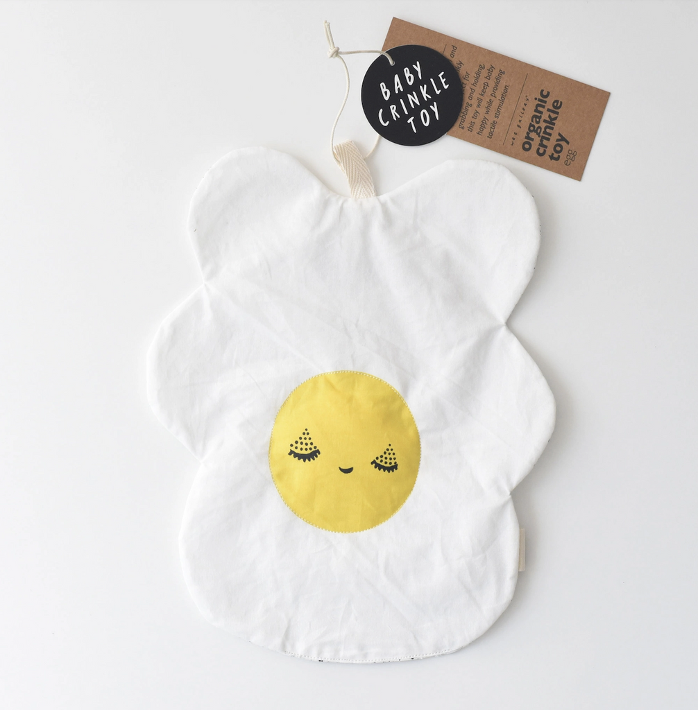 Baby crinkle toy shaped like a fried egg, made from organic cotton with bright yellow yolk in the center with a cute face. 