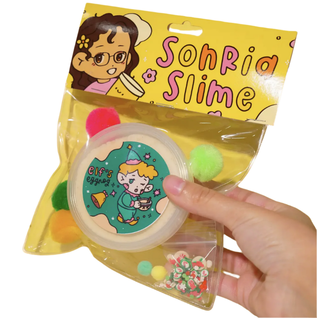 Sonria Slime brings you Elf's Eggnog scented slime packaged in a clear bag with the tub of slime, Christmas themed add ins and red and green pom poms. (Not food)