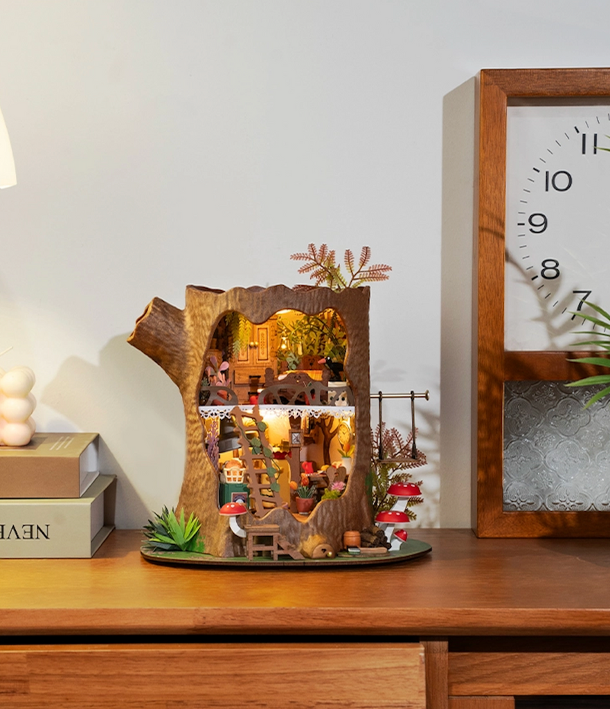 Fairytale Tree House DIY Miniature House Kit fully assembled, lit up and placed on a shelf. 