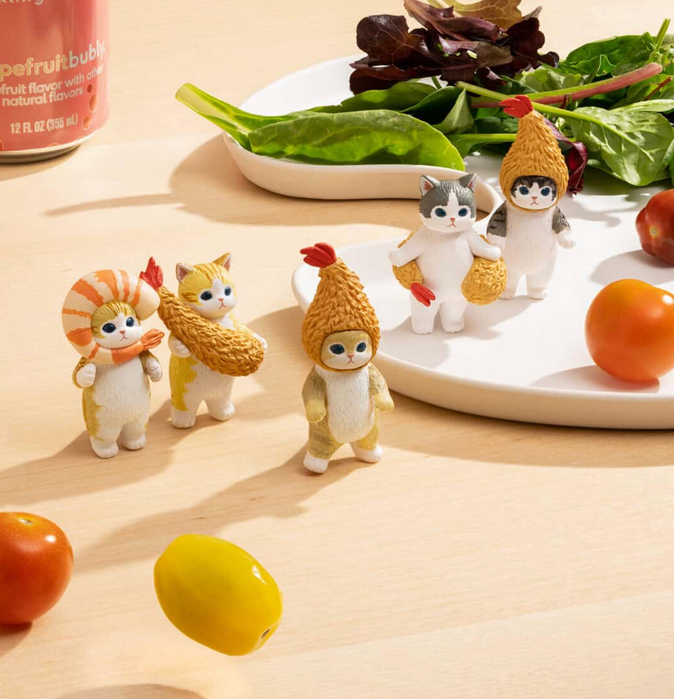 Mofusand Fried Shrimp Cat blind box collectible figures on a table near a salad.