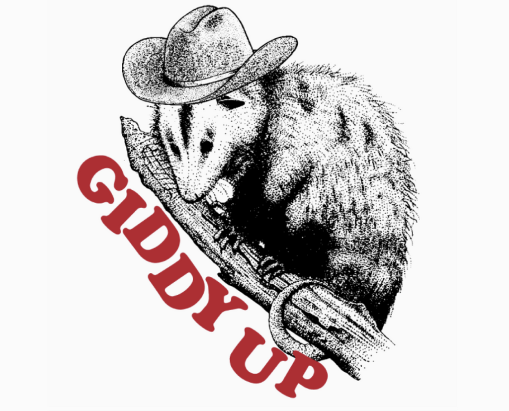 Close up of a sketch of a possum wearing a cowboy hat perched on a branch that reads "Giddy Up" in red letters, all printed on a white shirt.