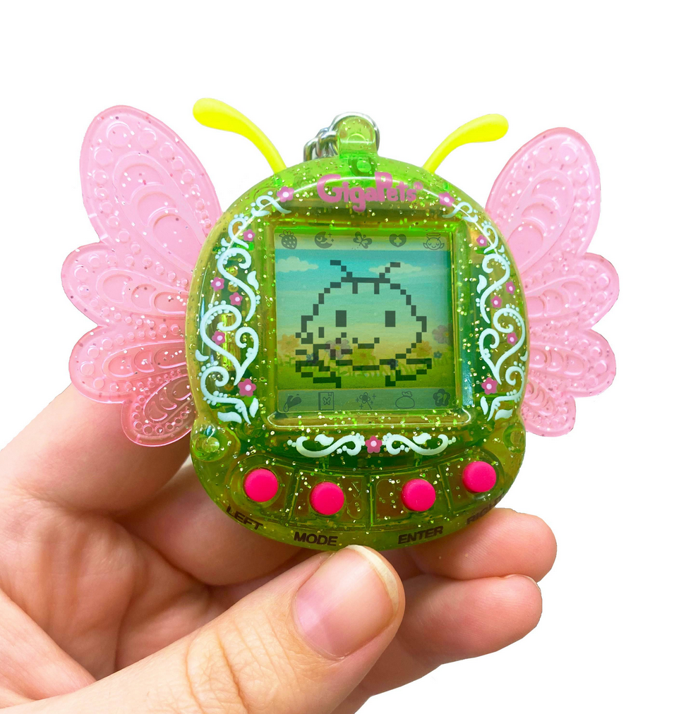 Green Pixie GigaPets with pink wings being held in a hand.