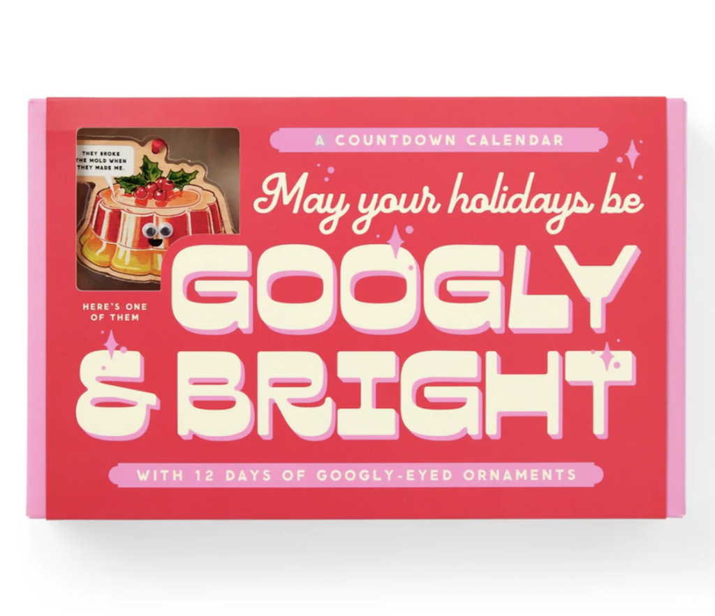 Bright red and pink box cover for the Googly & Bright Holiday Ornament Advent Calendar. In the top left corner  is a picture of one of the wooden ornaments included in the set with googly eyes attached and a word bubble that reads " They broke the mold when they made me" 