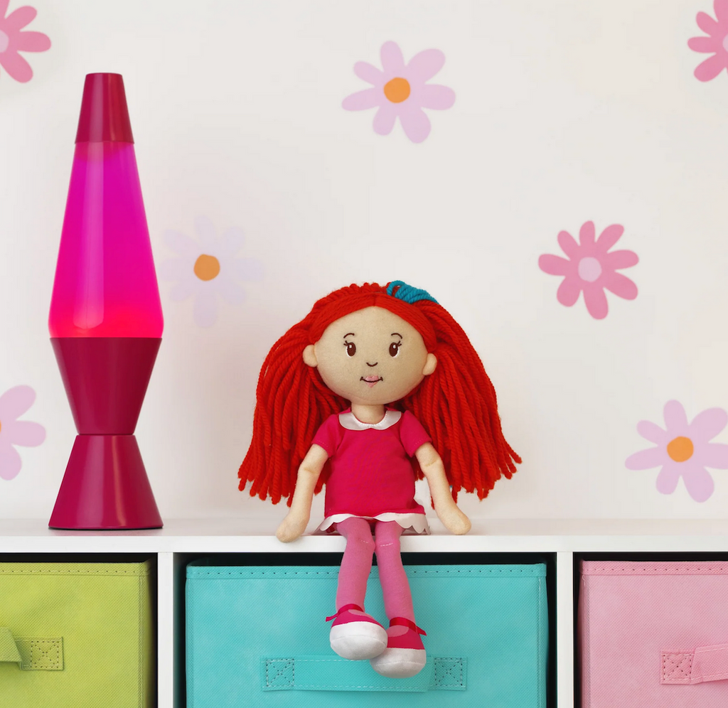 Groovy Girls doll Poppy sitting on shelf beside a pink lava lamp. 