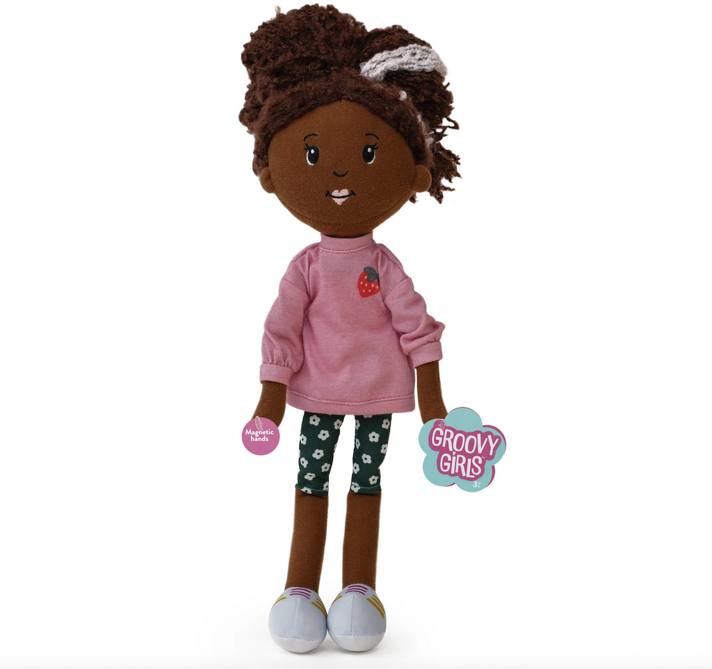 Groovy Girls doll Saige wearing a pink sweatshirt with a strawberry decoration and green leggings with a daisy print. 
