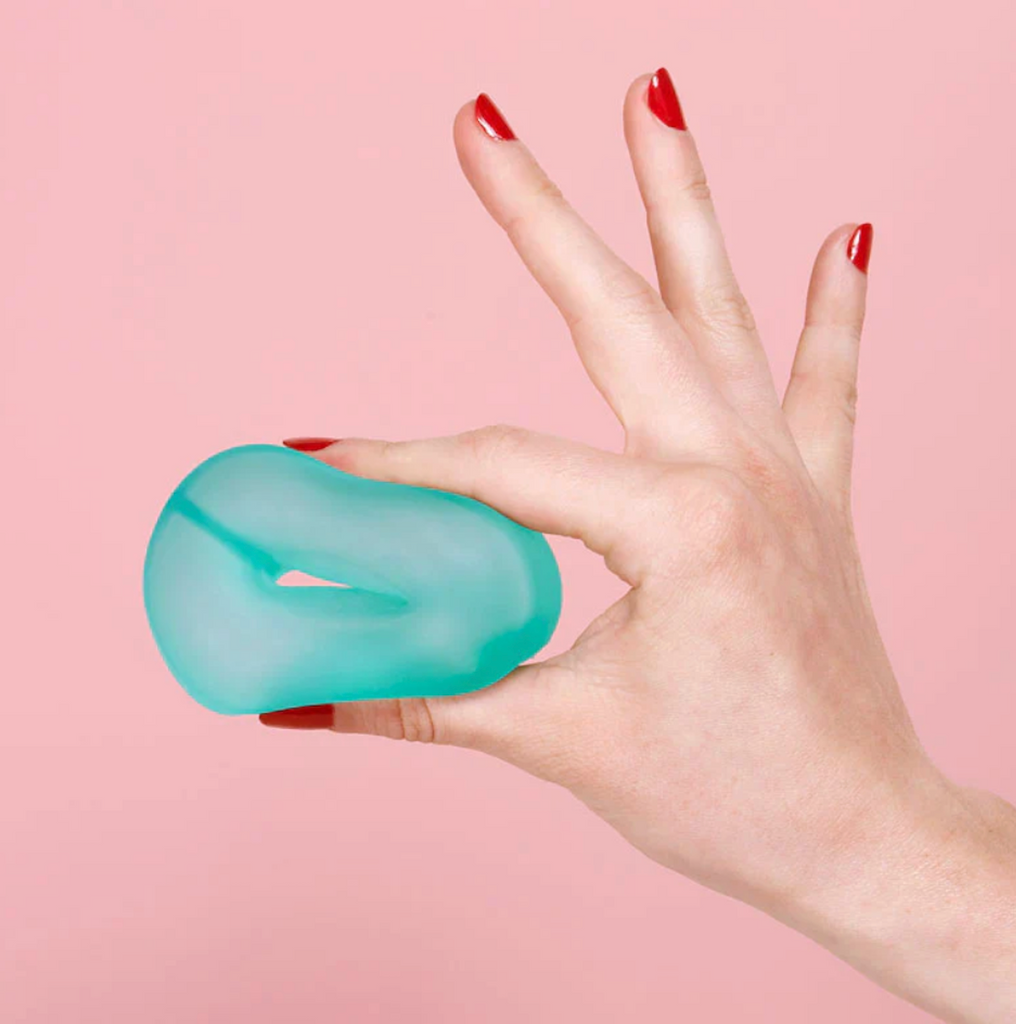 A hand squeezing the Gump Loop in the color Sea Glass. 