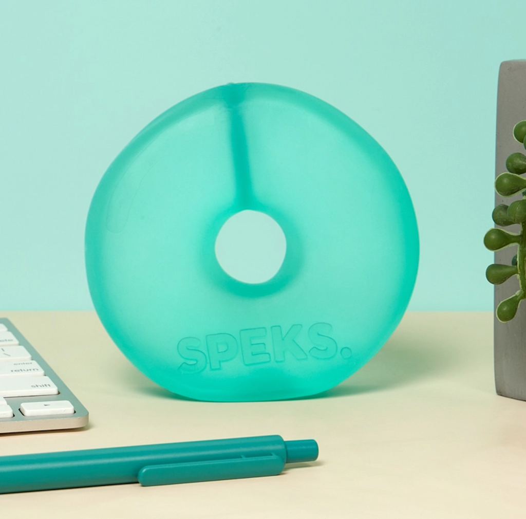 Speks Jumbo Loop in Sea Glass sitting on on a desktop beside a keyboard. 