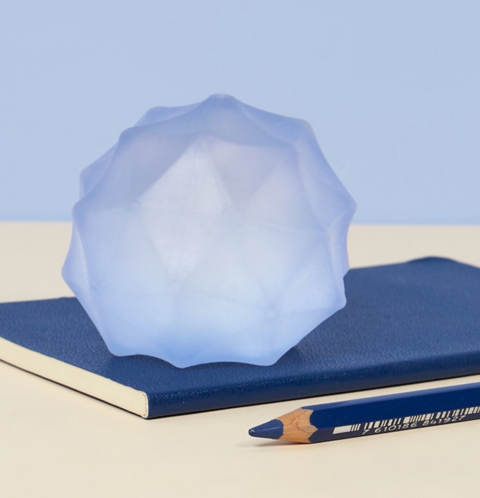 Textured light blue stress ball sitting on a notebook on a desk. 