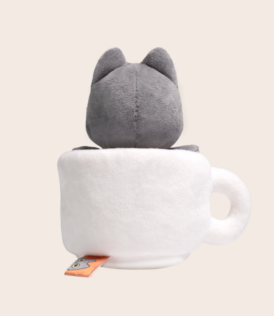 A plush toy featuring a gray cat sitting inside a white cup, shown from the back.