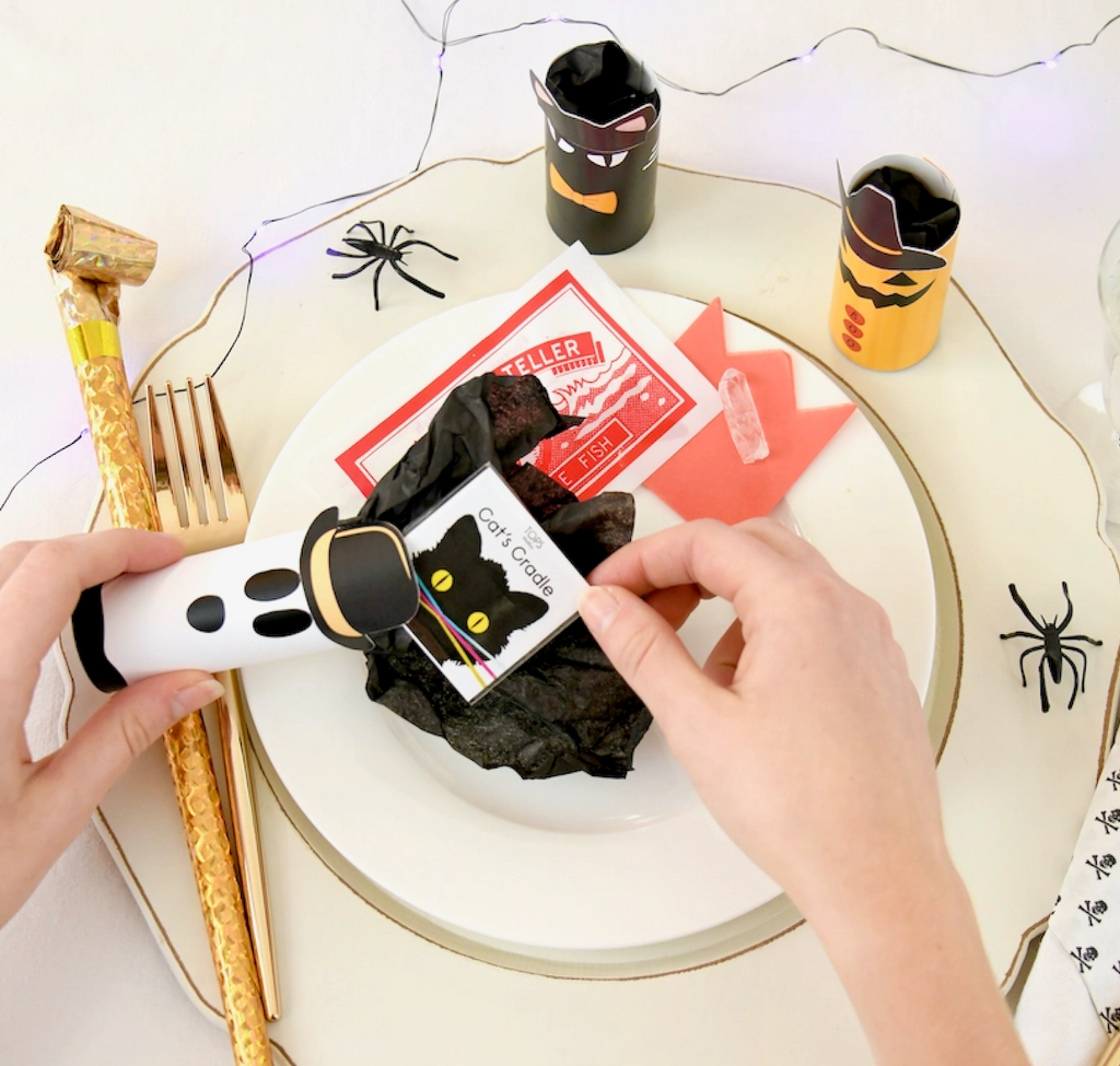 A Halloween Tabletop Surprise being opened at a Halloween place setting. 