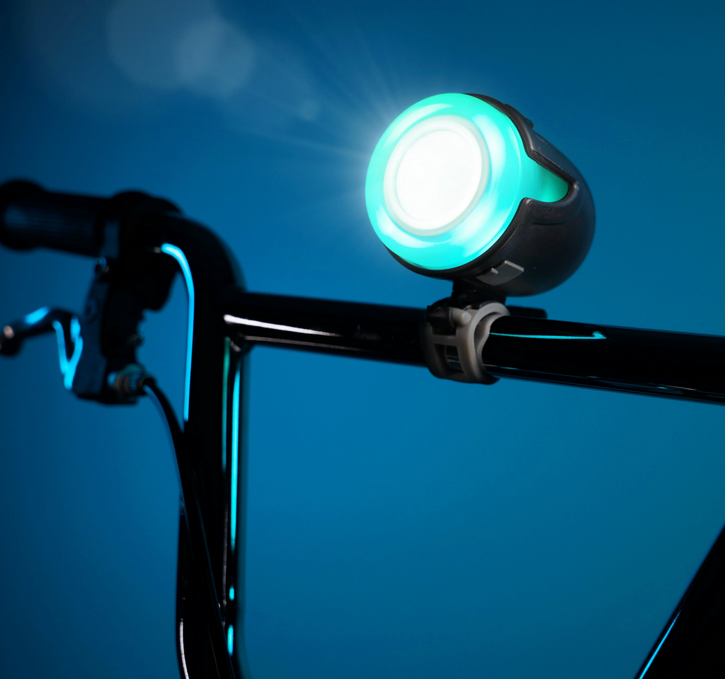 Halo Bightz bicycle headlight attached to the handlebars of a bike and illuminated with a blue light. 