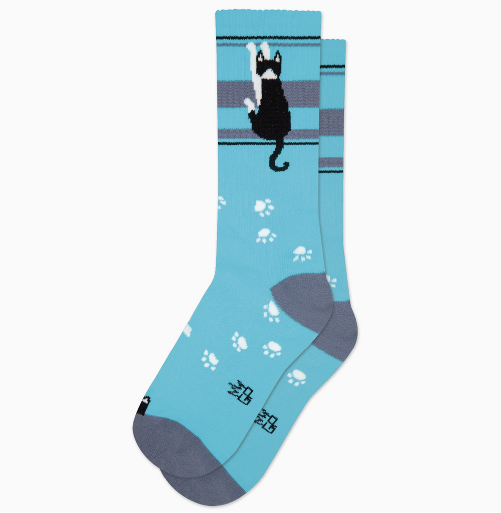 Light blue tube socks with grey stripes and a black and white kitty hanging. 