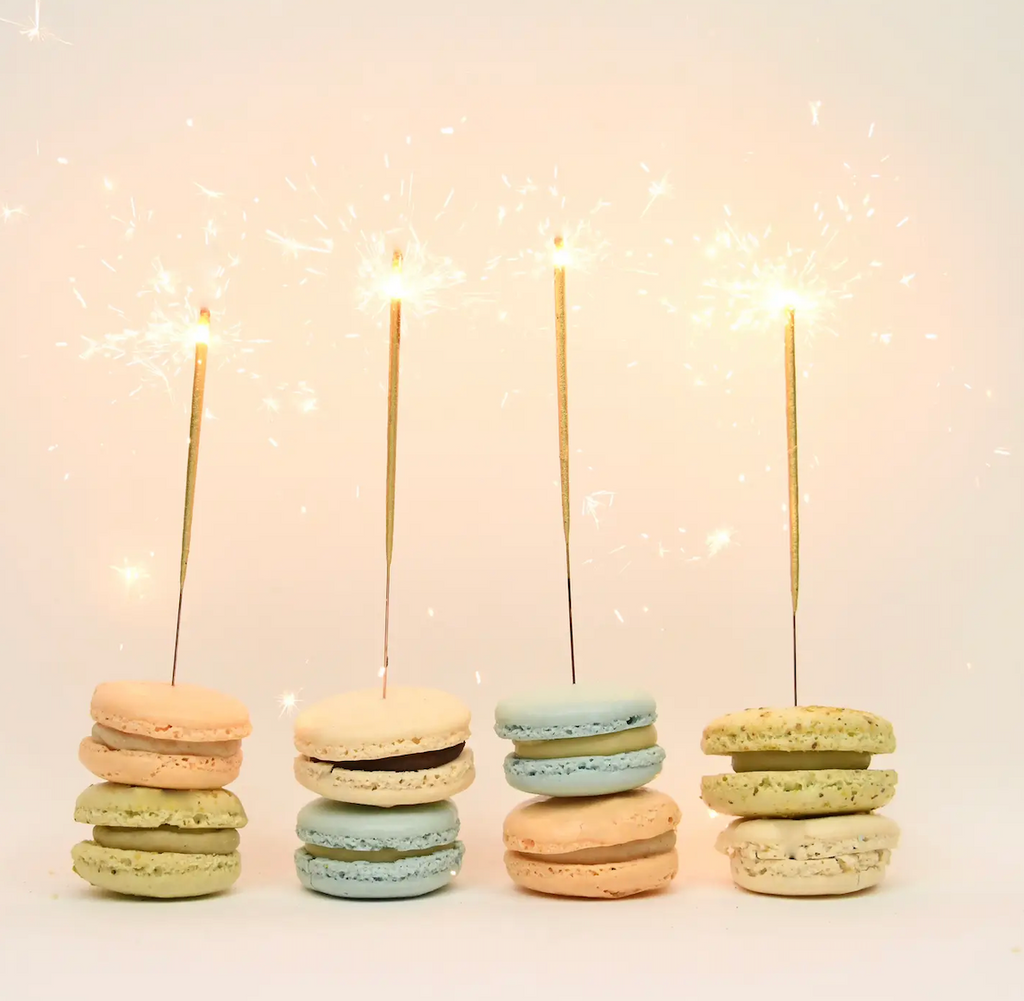 Colorful macaroons with mini gold sparklers burning in them. 